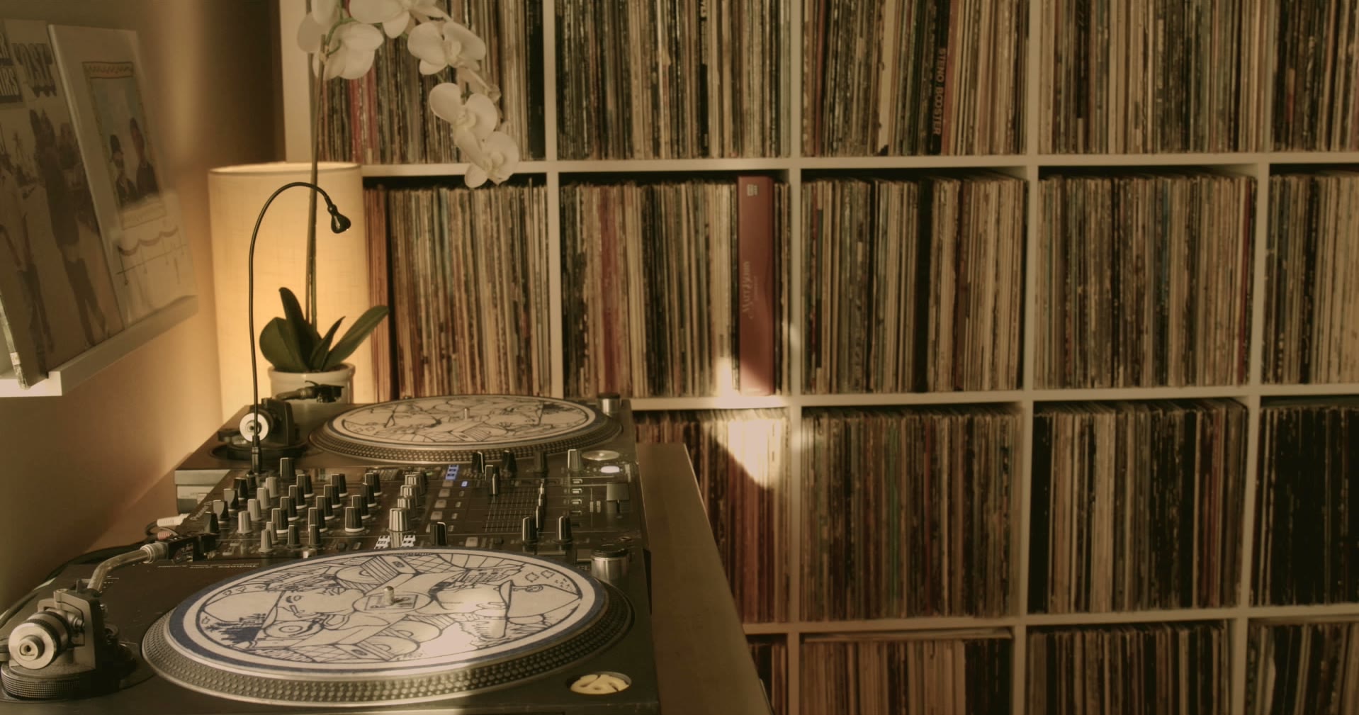 Two turntables and a mixer in front of shelves filled with records